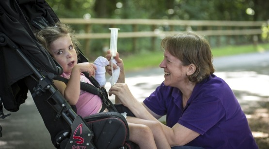 Girl in wheelchir being tube fed by a carer
