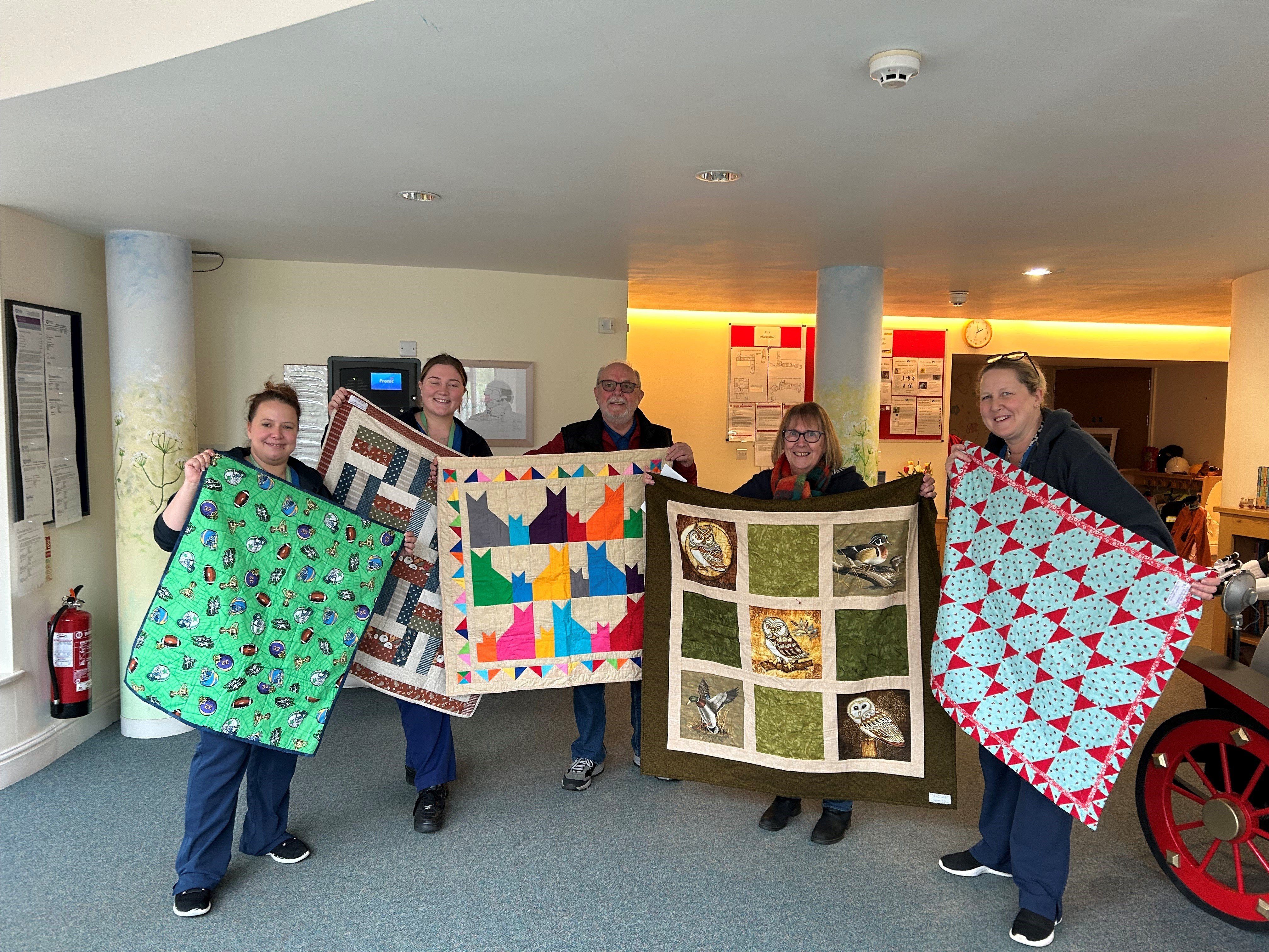 Members of Project Linus hand quilts to care staff at Charlton Farm