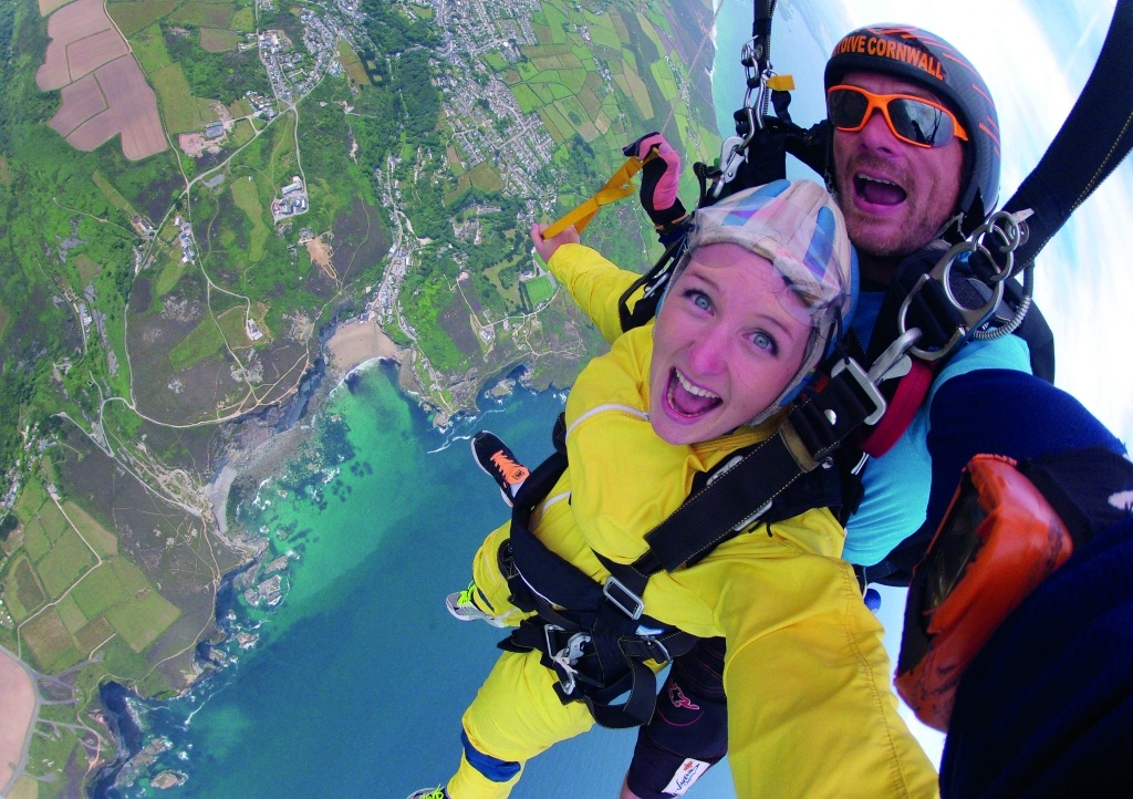 Lady skydiving over Cornish coastline