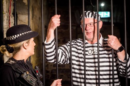 Prisoner behind bars with Police Officer at CHSW Jail and Bail fundraising event at Bodmin Jail