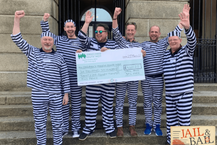 Prisoners standing on steps celebrating with giant cheque