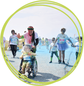 Dad pushing boy in wheelchair at Rainbow Run