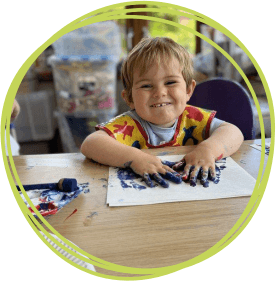 Little boy smiling while doing messy play painting