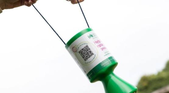 Two hands holding a CHSW collection tin with a QR code on it