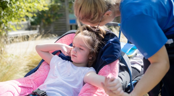 Little girl in wheelchair and nurse leaning over her
