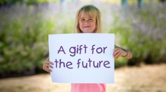 Girl holding a card that says 'a gift for the future'