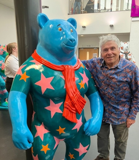 man standing next to large sculpted bear