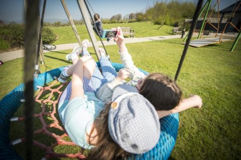 Siblings on swing with phone