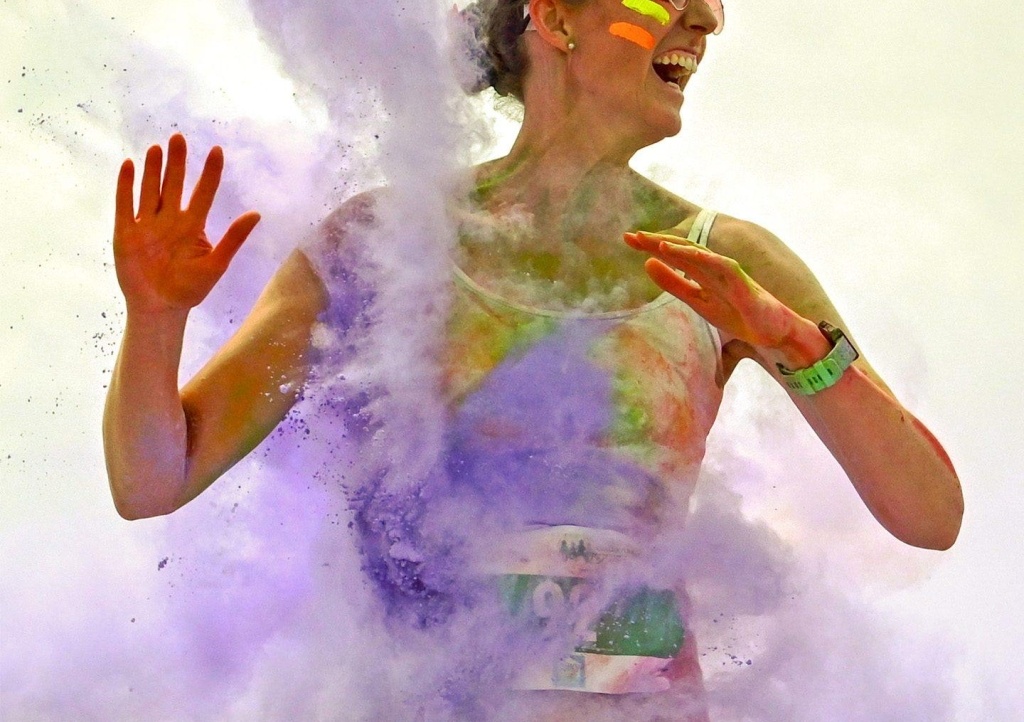 Woman smiling and being spattered with purple powder paint