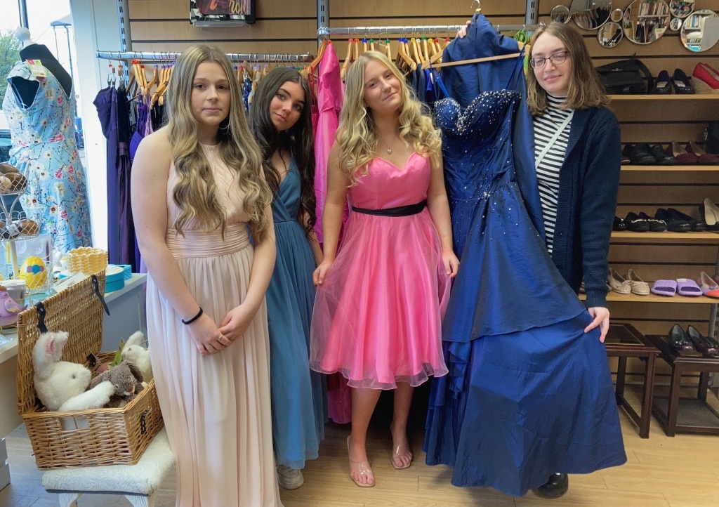 Honiton Community College students try on some of the dresses with shop volunteer Emma Weir