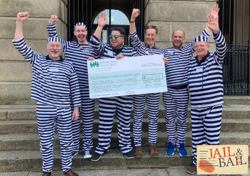 Prisoners standing on steps celebrating with giant cheque