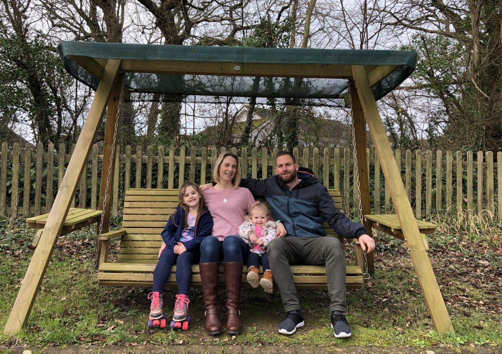 Family of four sitting on garden swing bench