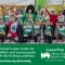 Group of people wearing green running vests with their hands raised