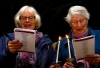 Two ladies singing carols at candlelight