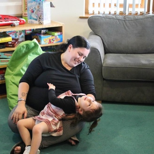 Mum itting on the floor hugging daughter