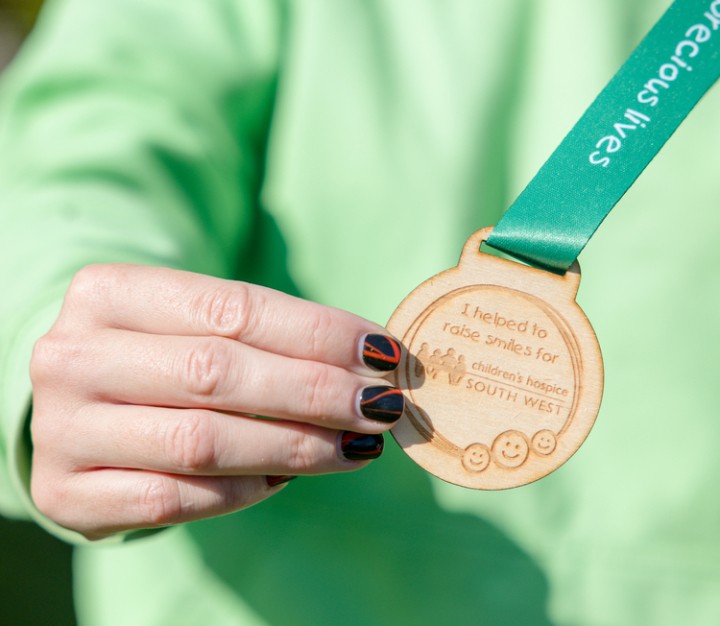 Hand holding CHSW green wooden medal