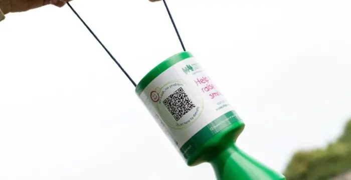 Two hands holding a CHSW collection tin with a QR code on it