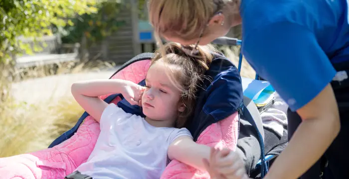 Little girl in wheelchair and nurse leaning over her