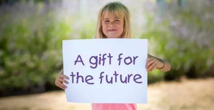 Girl holding a card that says 'a gift for the future'