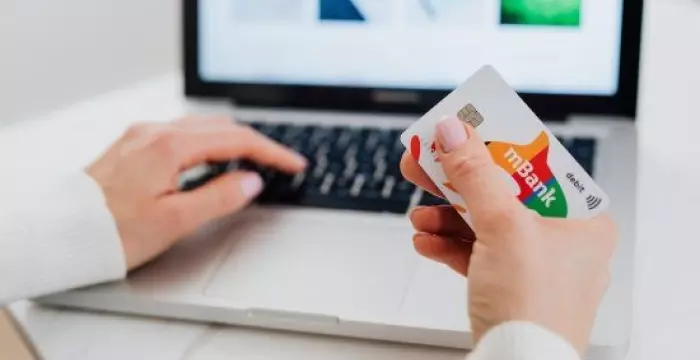 Hands on a white and black laptop with shopping online credit card in hand Hands on a white and black laptop with shopping online credit card in hand