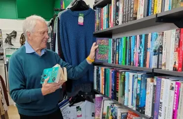 Volunteer stocks books at a charity shop