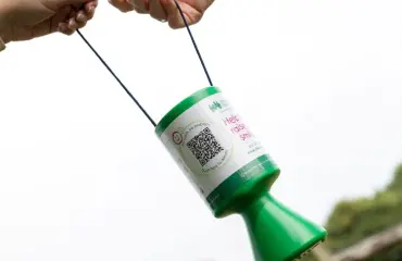 Two hands holding a CHSW collection tin with a QR code on it