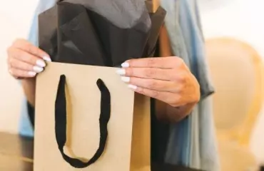 Brown paper shopping paper with black handles held by woman Brown paper shopping paper with black handles held by woman